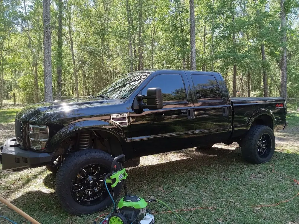 Black Ford F-250 with black wheels, pressure washer in front