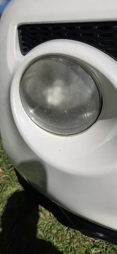 Hazy, cloudy fog light on a white Nissan Juke before restoration